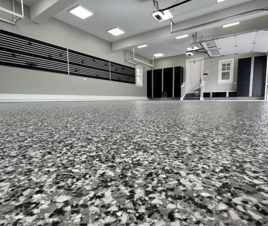 Residential garage with epoxy floor coating and decorative flake finish, gray and black color blend.