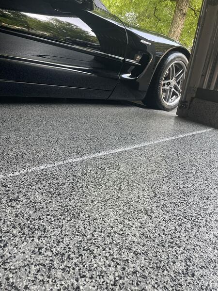 Concrete coating on garage floor with a black car in the garage.