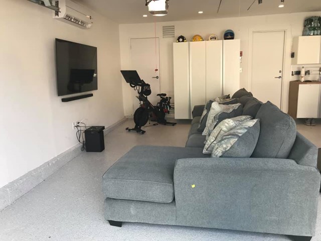 Couch, cabinets, tv, and excercise bike in a garage.